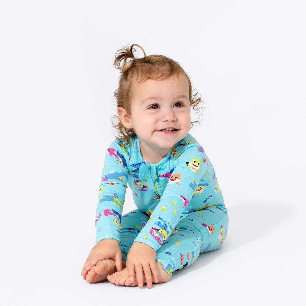 Bellabu Bear Bamboo Convertible Footie Baby Shark worn by a smiling toddler in a blue print, sitting on a white studio backdrop.