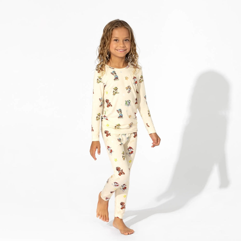 Bellabu Bear Bamboo Kids Pajamas Paw Patrol set worn by a smiling girl walking barefoot in cream loungewear.