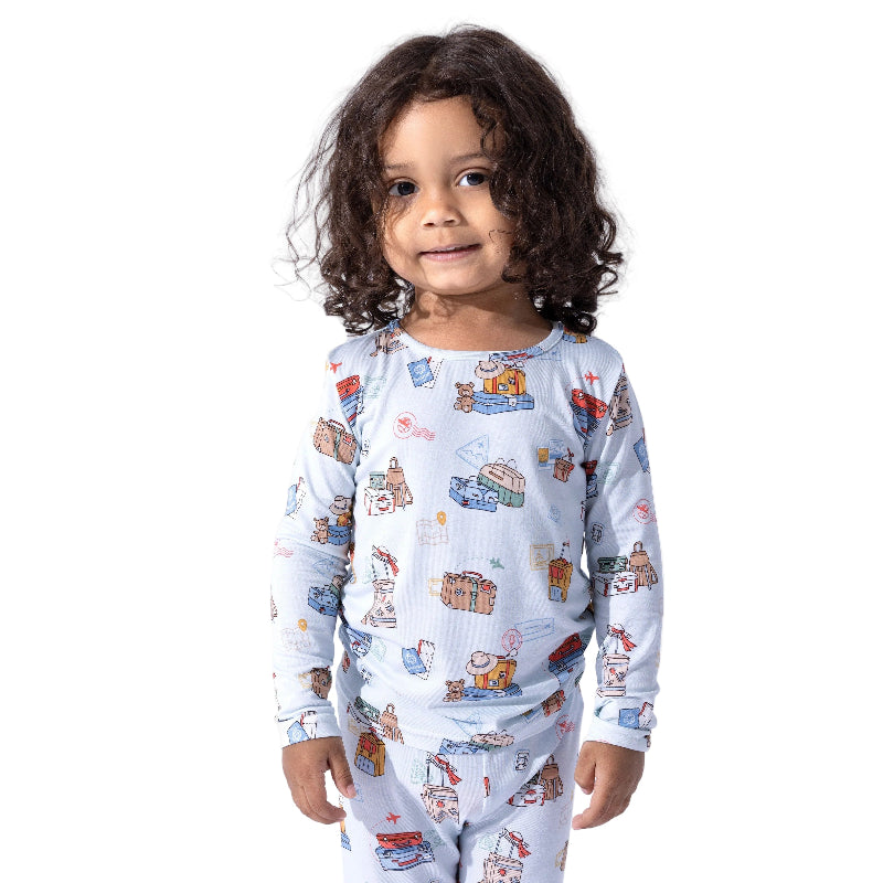 Bellabu Bear Bamboo Kids Pajamas Vintage Suitcases worn by a smiling toddler in light blue printed pajamas.