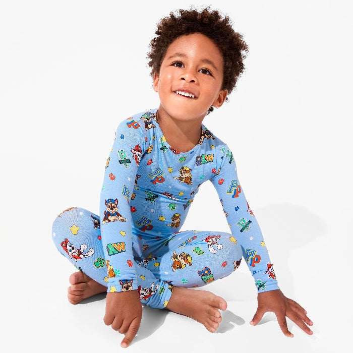 Bellabu Bear Varsity Blue Bamboo Kids Pajamas with Paw Patrol; child sits cross-legged smiling in printed set.