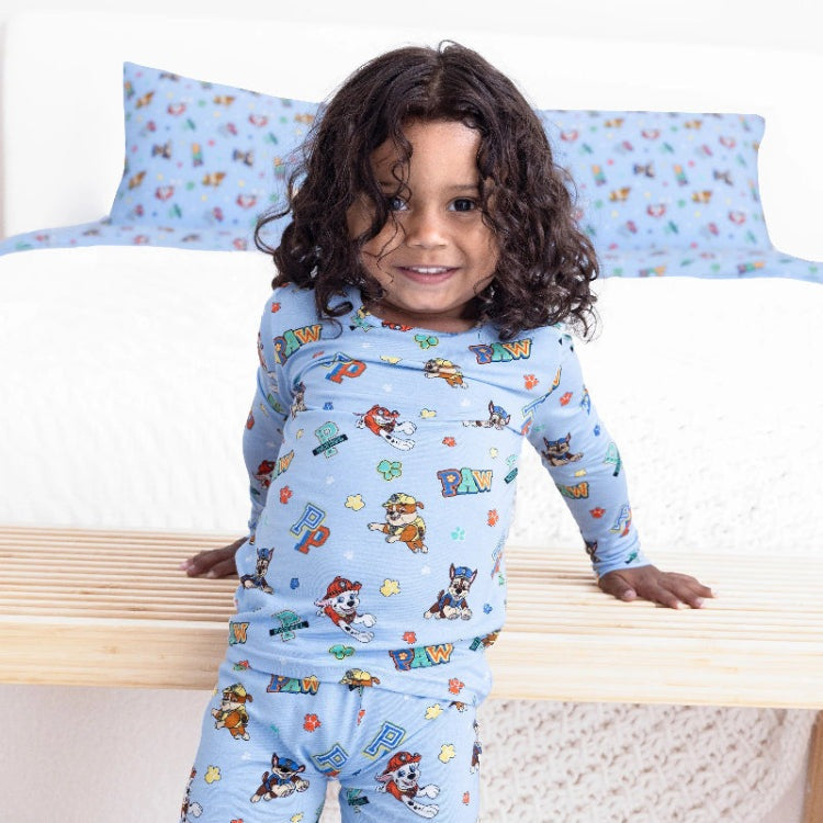 Bellabu Bear Varsity Blue Bamboo Kids Pajamas Paw Patrol: child stands on a bed in blue bamboo PJ set.