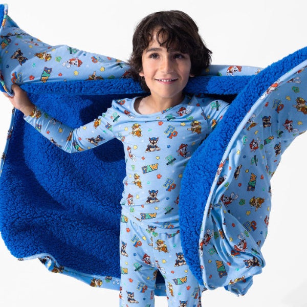 Bellabu Bear Varsity Blue Bamboo Kids Pajamas Paw Patrol with plush blue fleece blanket opened around the child.