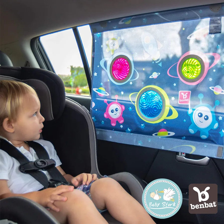 Benbat Car Sunshade With Dazzle Effect Square, with hanger, attached to car window beside a strapped toddler.