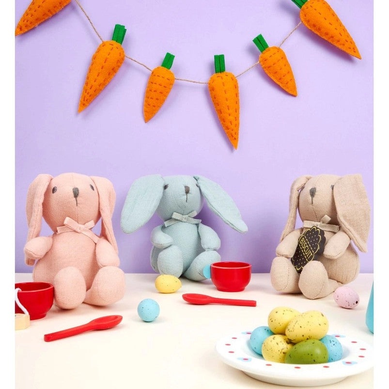 Best Years cotton bunny stuffed toy in teal with two pastel bunny siblings, colorful Easter eggs on a white table