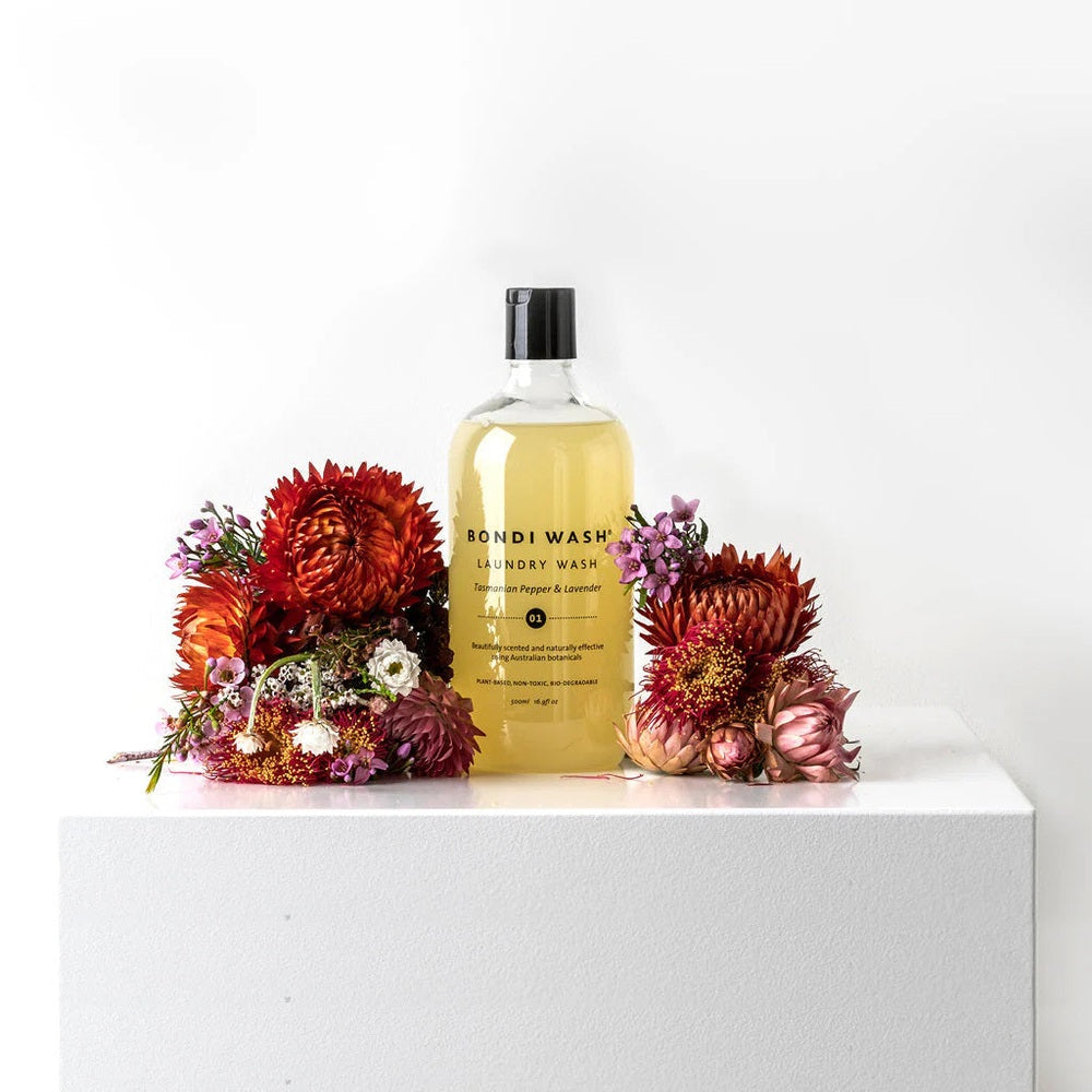 Bondi Wash Laundry Wash Tasmanian Pepper & Lavender 1L bottle surrounded by vibrant red and orange flowers.