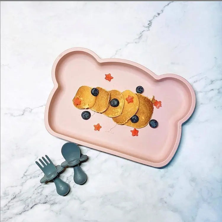 Bopomofo Bear Silicon Plate in pink holding stacked pancakes with blueberries; three grey toddler utensils beside.