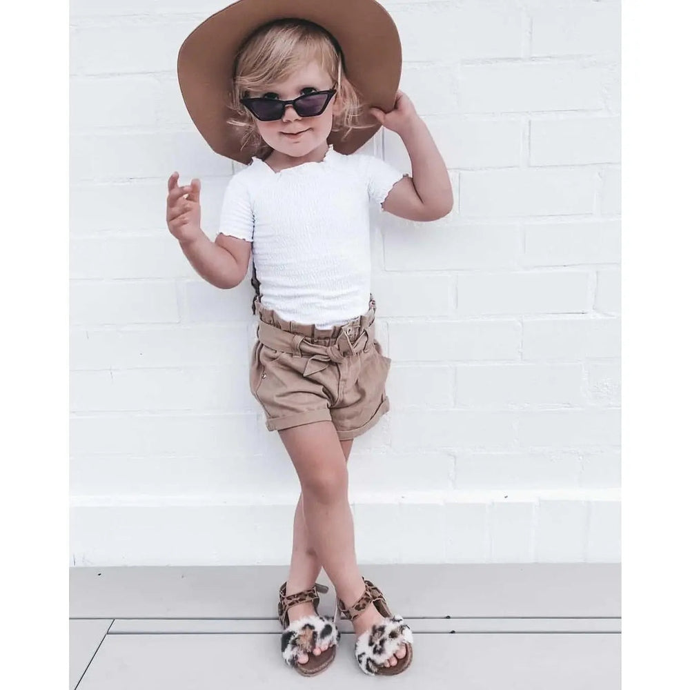 Boxbo Cork Sandal Leon Leopard sandals on a kid in white tee and tan shorts, leopard-print straps with cork sole.