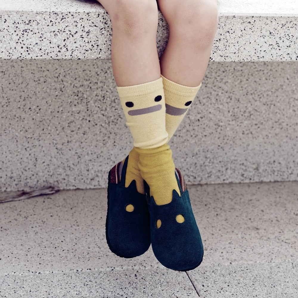 Boxbo Fox Cork Clog sandals in blue worn by a child sitting with crossed legs on steps, yellow socks visible.