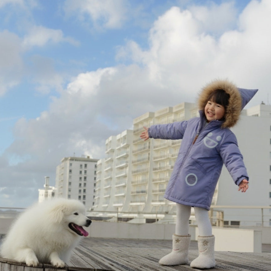 Boxbo Wistiti fleece-lined waterproof fur jacket in mauve lavender, worn by a smiling child with a fur-trim hood on a rooftop.