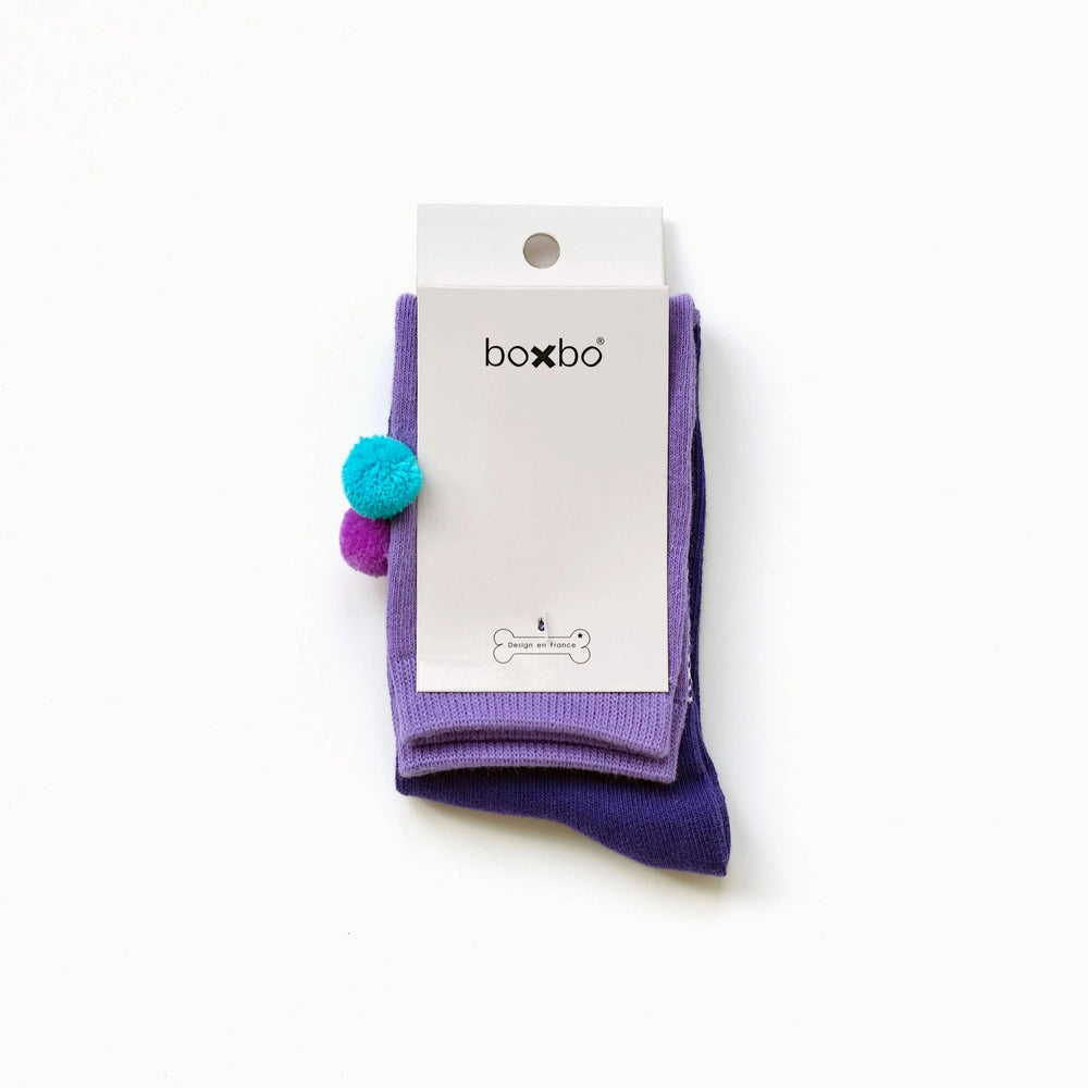 Boxbo Wistiti High Sock Violet, purple knit baby sock shown folded with turquoise pom pom accents and white tag.