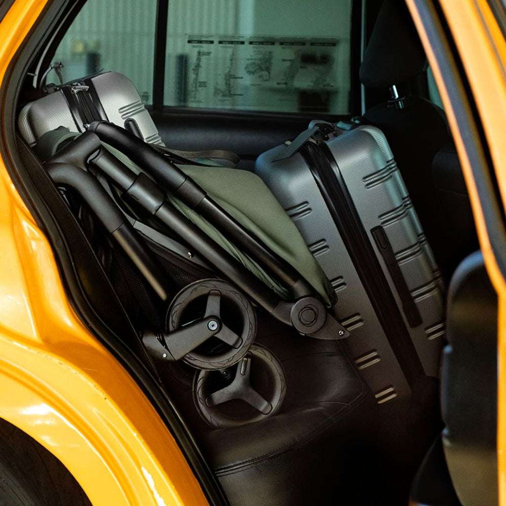 Bugaboo Butterfly 2 stroller folded in car trunk, wheels visible, black and gray