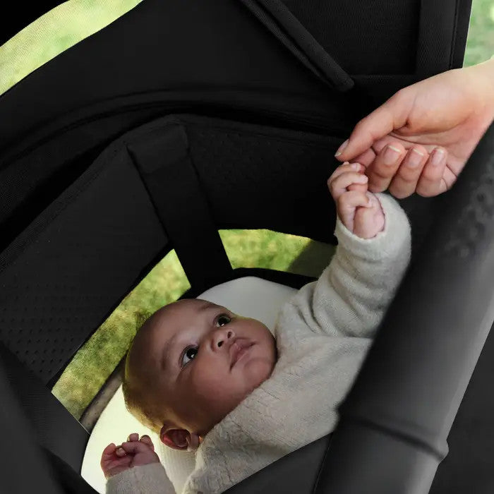 Bugaboo Fox 5 Renew Complete Stroller, black frame with lime accent; baby in light sweater reaches up to caregiver's hand.