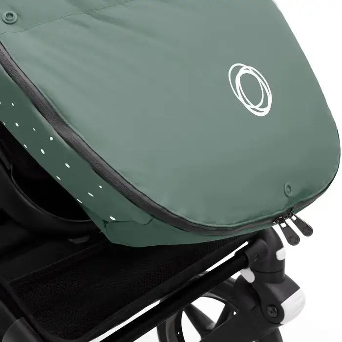 Bugaboo Performance Winter Footmuff in green weatherproof fabric, zipper opened on a Bugaboo stroller.
