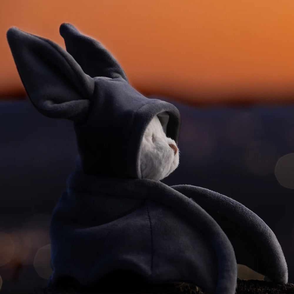 Bukowski Bears Ziggy Bat stuffed animal in navy plush hoodie, showcasing soft, cuddly toy appeal at sunset.