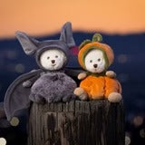 Bukowski Bears Ziggy Pumpkin stuffed animals sit on a wooden stump, one bat-costumed and one pumpkin-costumed, cozy Halloween cuddle.