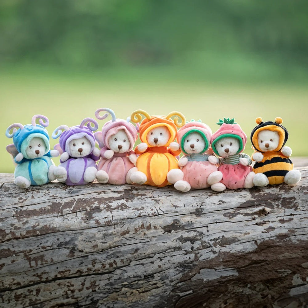Bukowski Bears Ziggy Strawberry stuffed animals lineup in pastel fruit-hood outfits perched on a weathered log