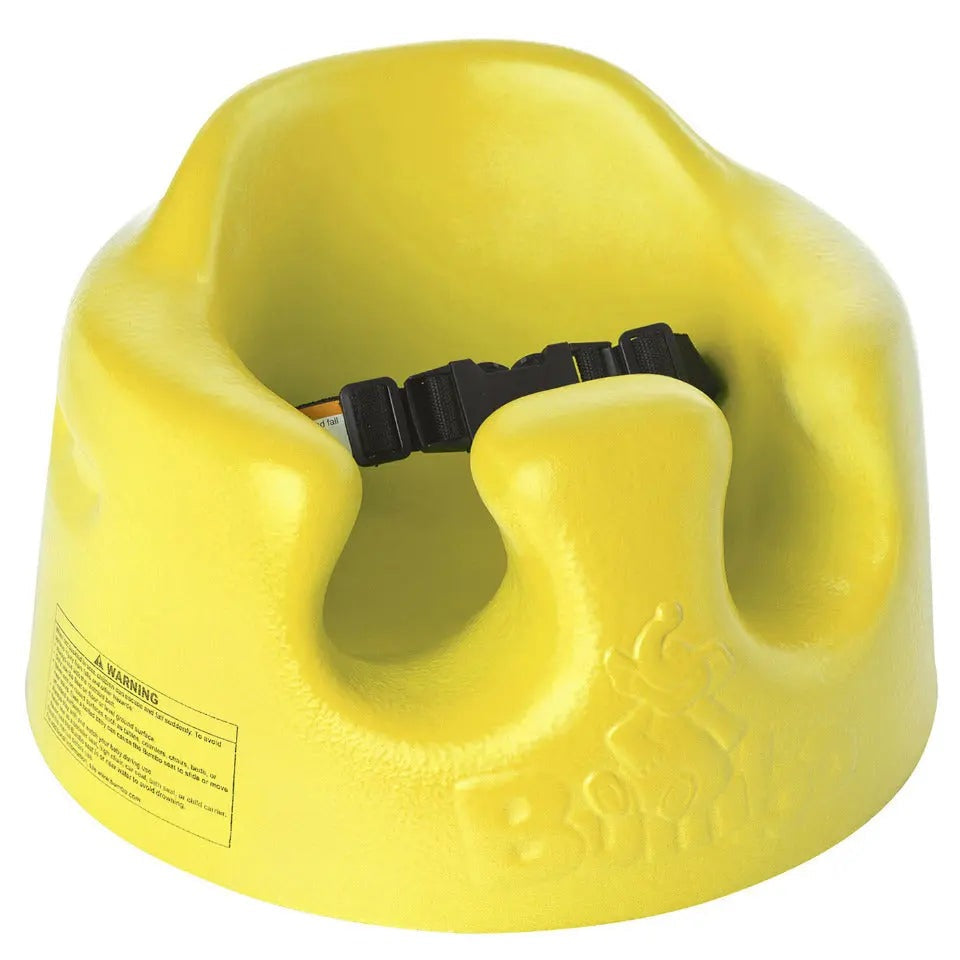 Bumbo Floor Seat in bright yellow foam, black safety strap fastened, ready for secure toddler seating.