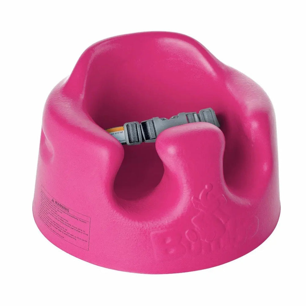 BUMBO Floor Seat pink booster with adjustable grey safety strap fastened around the seat.