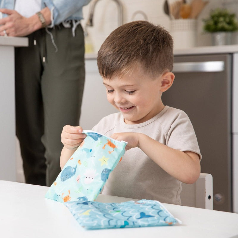 BUMKINS Large Snack Bag 2pk Ocean Life; blue ocean print, child opening one at kitchen table