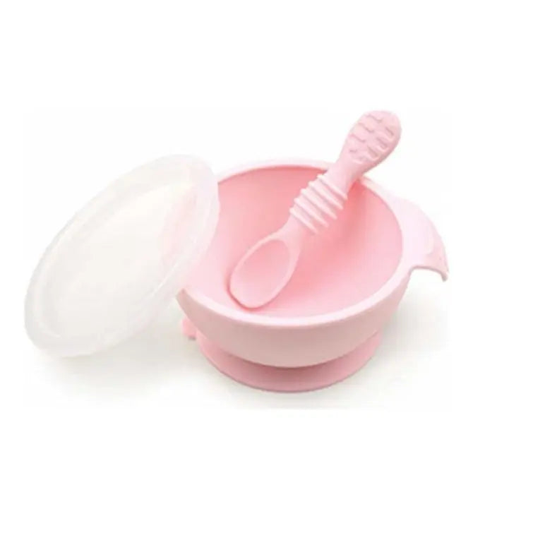 Bumkins Silicone First Feeding Set in pink with lid and spoon resting inside the bowl