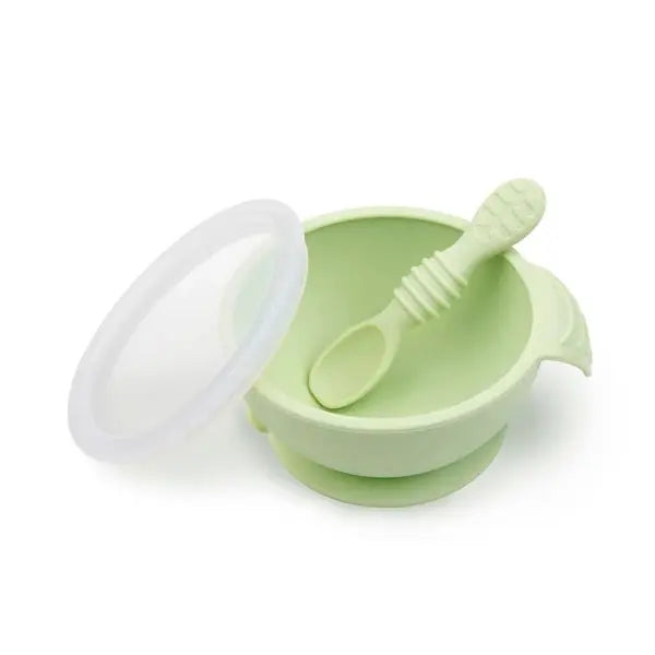 BUMKINS Silicone First Feeding Set in light green with suction bowl, lid, and spoon secured to a surface.