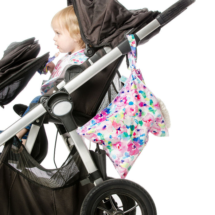 Bumkins Wet Bag Watercolour Flower in multicolor floral print hanging on stroller