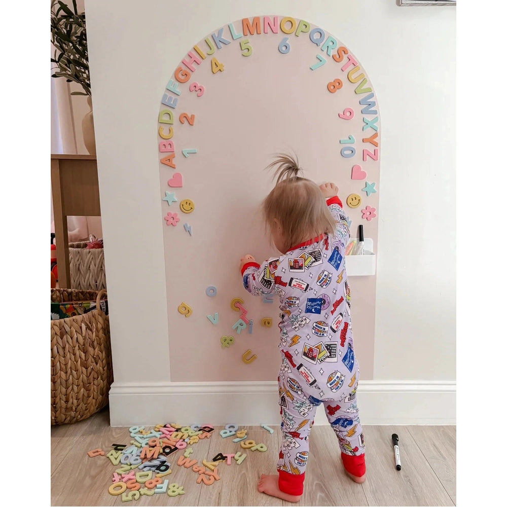Cherrypick Soft Foam Magnetic Letters & Symbols 150pc Set in pastel colors around a wall arch with a toddler playing.