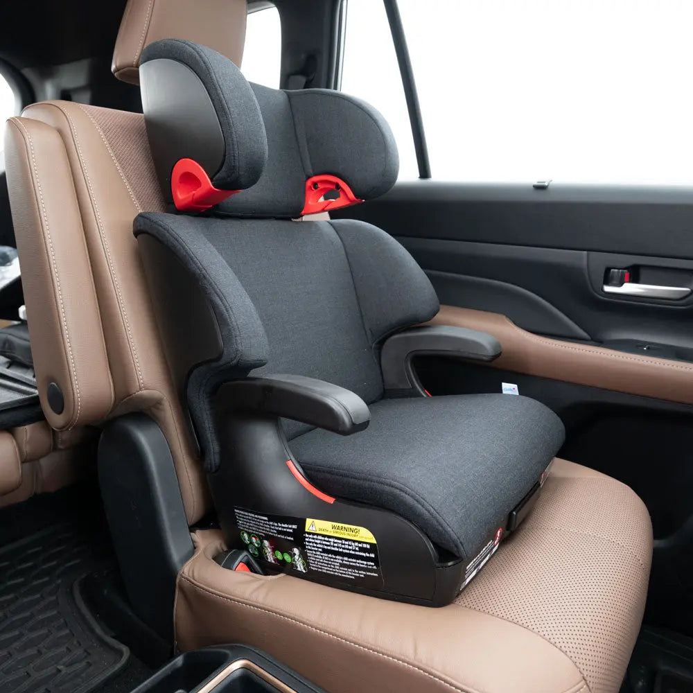 Clek Boost Seat Oobr booster installed on tan leather car seat, dark gray fabric with red guides showing secure mounting.