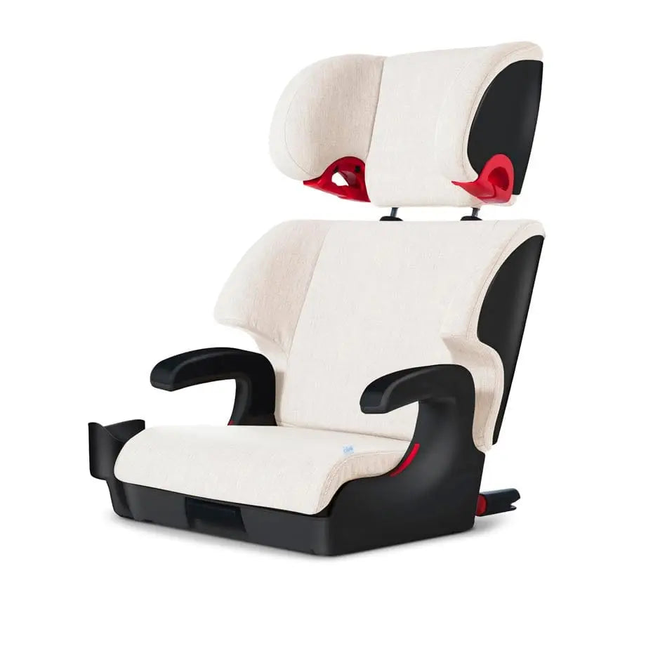 Clek Boost Seat Oobr booster in ivory beige fabric with black base; headrest, armrests, and red belt guides visible.
