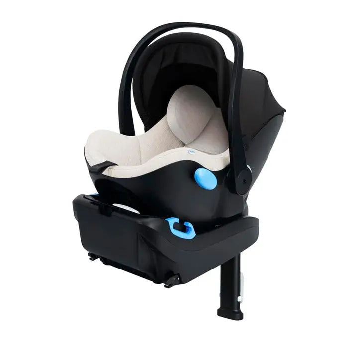 CLEK Liing infant car seat in black shell with beige interior, securely mounted on its base with a blue latch knob.