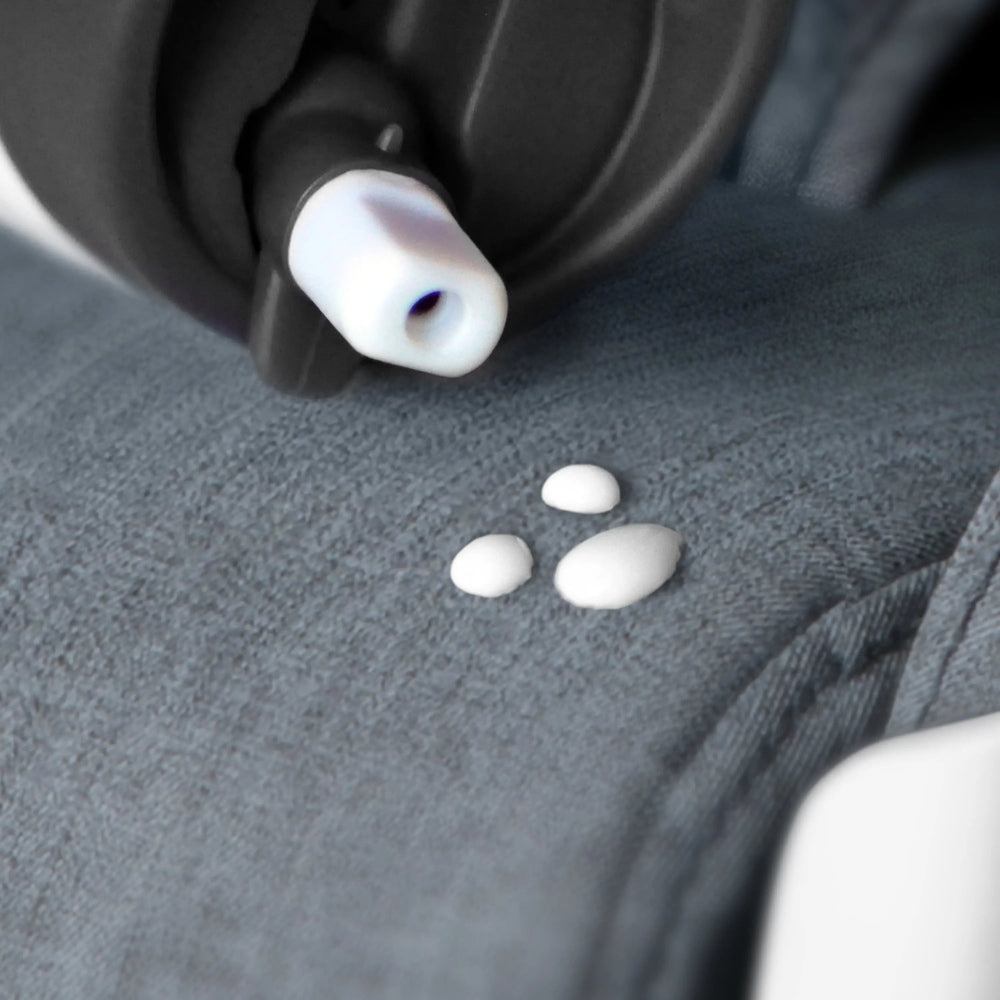 Clek Infant Car Seat Liing, white plastic nozzle with three small beads resting on gray car-seat fabric.