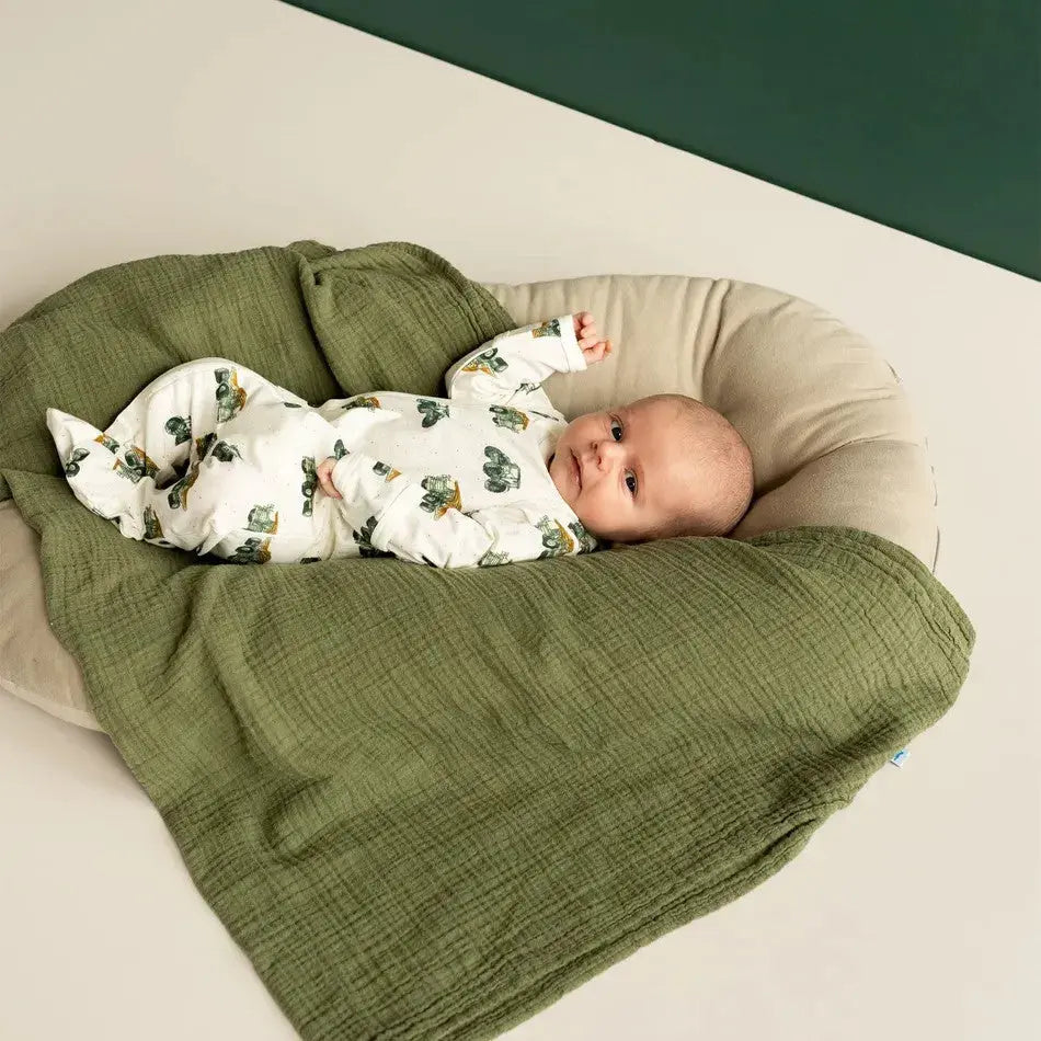 COCCOLI Coccoli Infant Cotton TENCEL Modal Zip Footie Cream Tractors: baby in tractor-print cream zipfootie snuggled on a green quilted blanket.