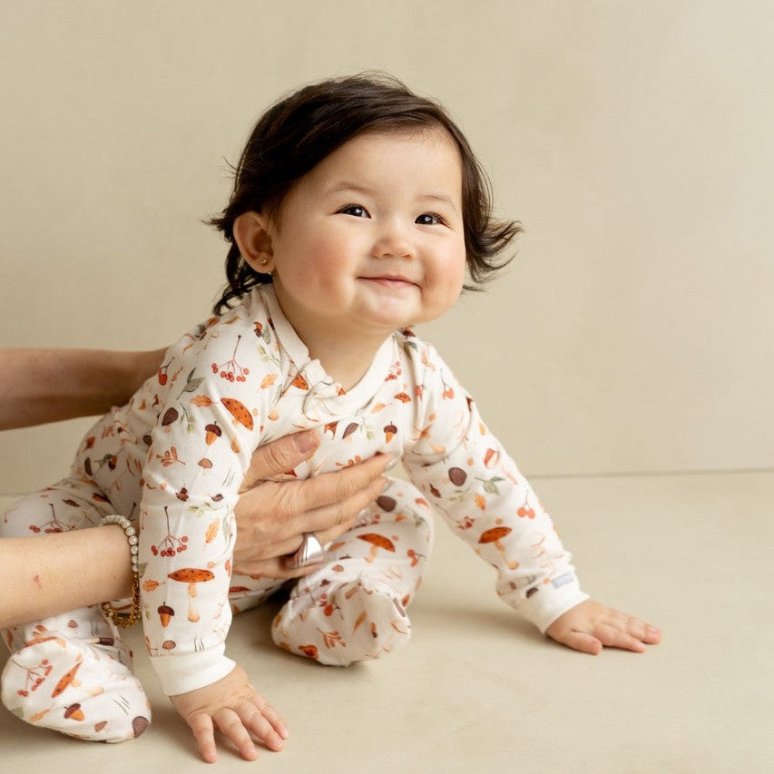 Coccoli Infant Cotton TENCEL™ Modal Zipper Footie Mushrooms On Cream; baby crawls with a parent’s gentle hold.