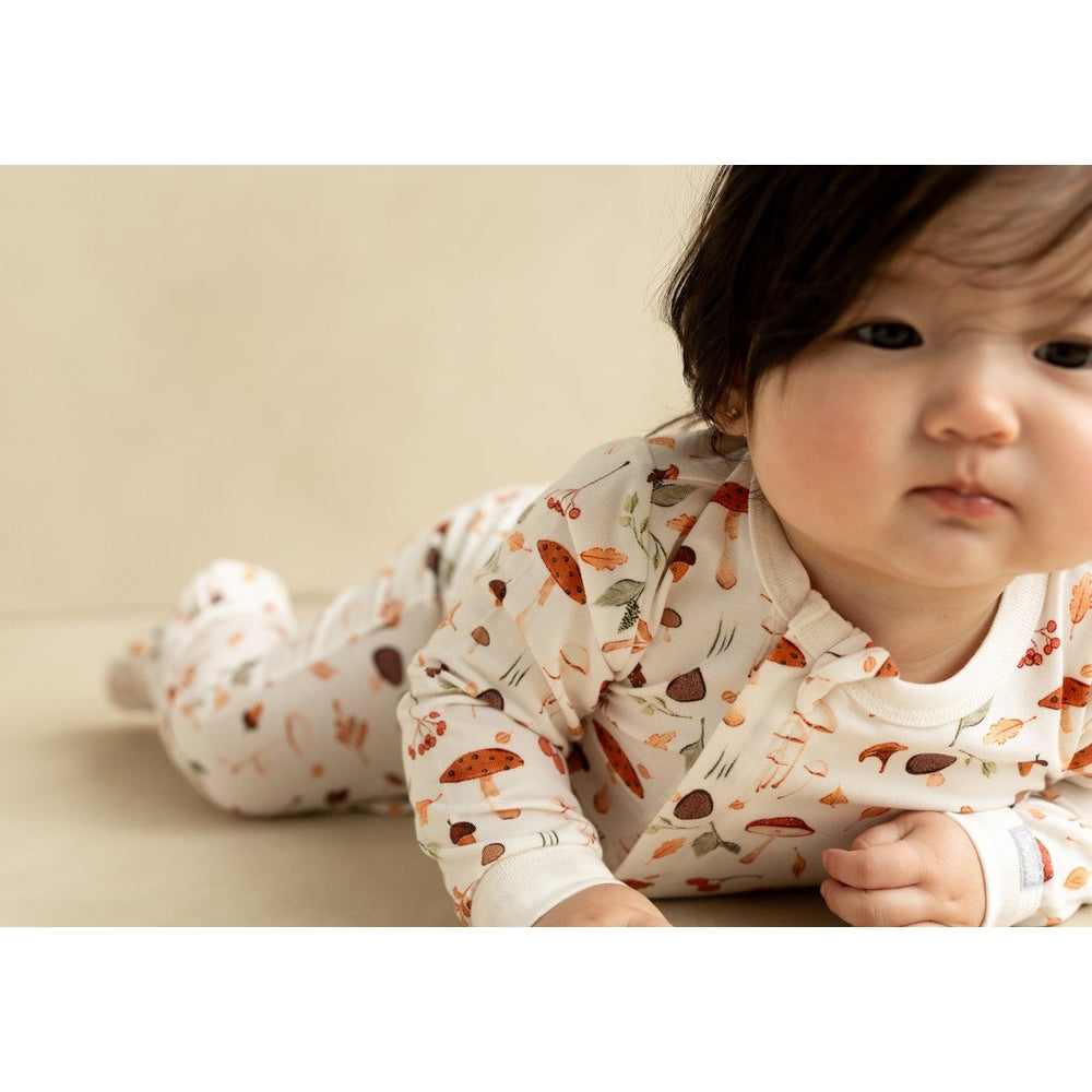 Coccoli Infant Cotton TENCEL™ Modal Zipper Footie Mushrooms On Cream, baby crawls in cream mushroom-printed one-piece.