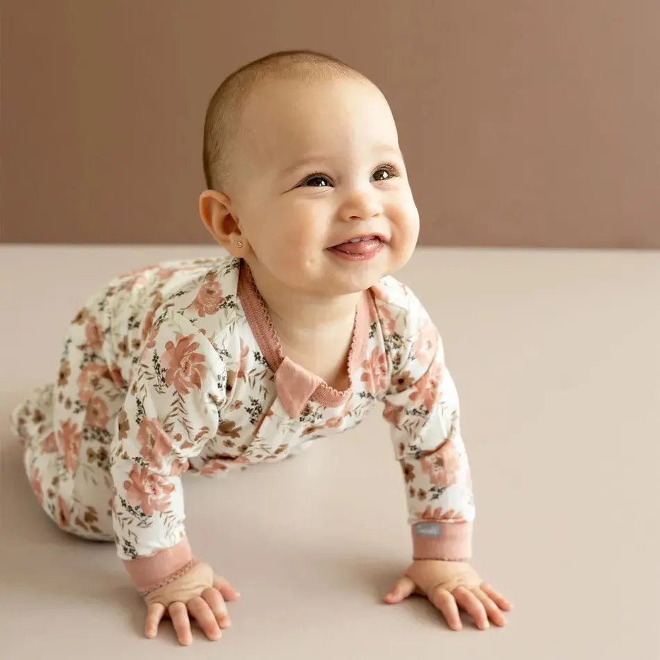 Coccoli Infant Floral Cotton TENCEL™ Modal Zip Footie; baby crawls on hands in pink-cuffed floral sleeper.