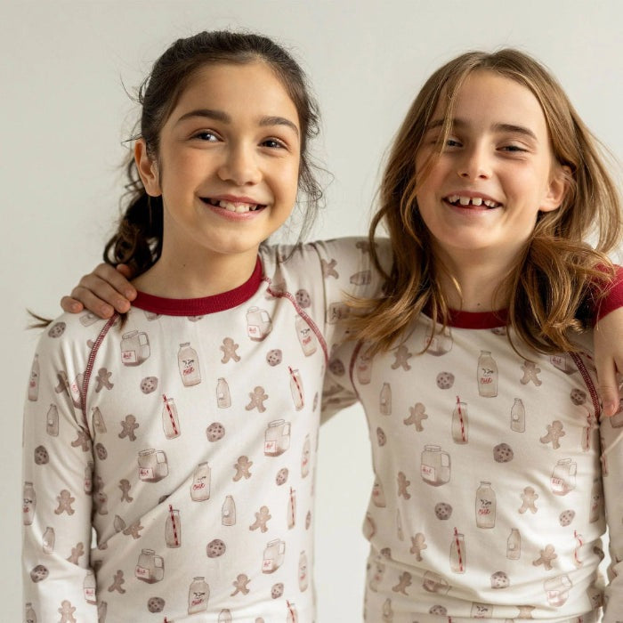 Coccoli Kids long sleeve cookie-print pajamas in cotton TENCEL™ Modal with red trim; two girls in matching sets.