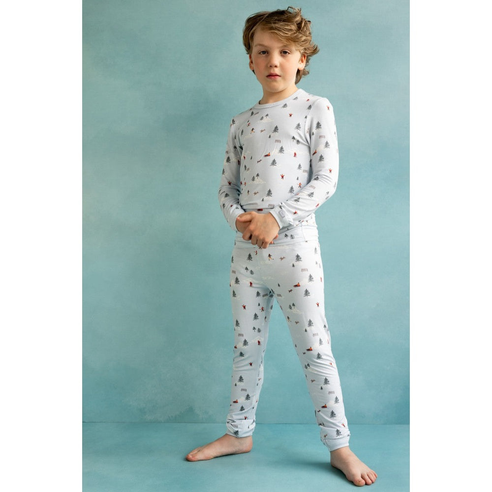 Coccoli Kid Long-Sleeved Cotton TENCEL™ Modal Pajama Set in light blue; boy stands barefoot, clasping hands to show soft, cozy winter print.