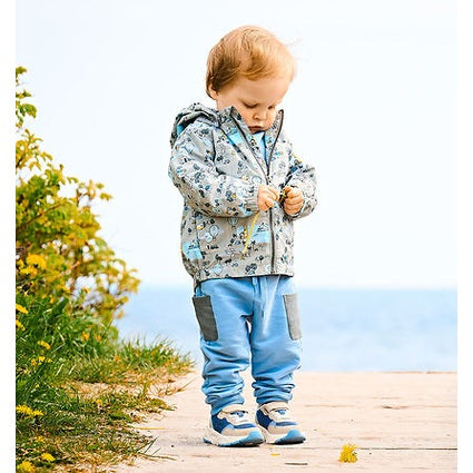 Color Kids Girls Baby Jacket Dusty Green worn by a toddler by the sea, zipping the jacket with blue accents and gray pockets.