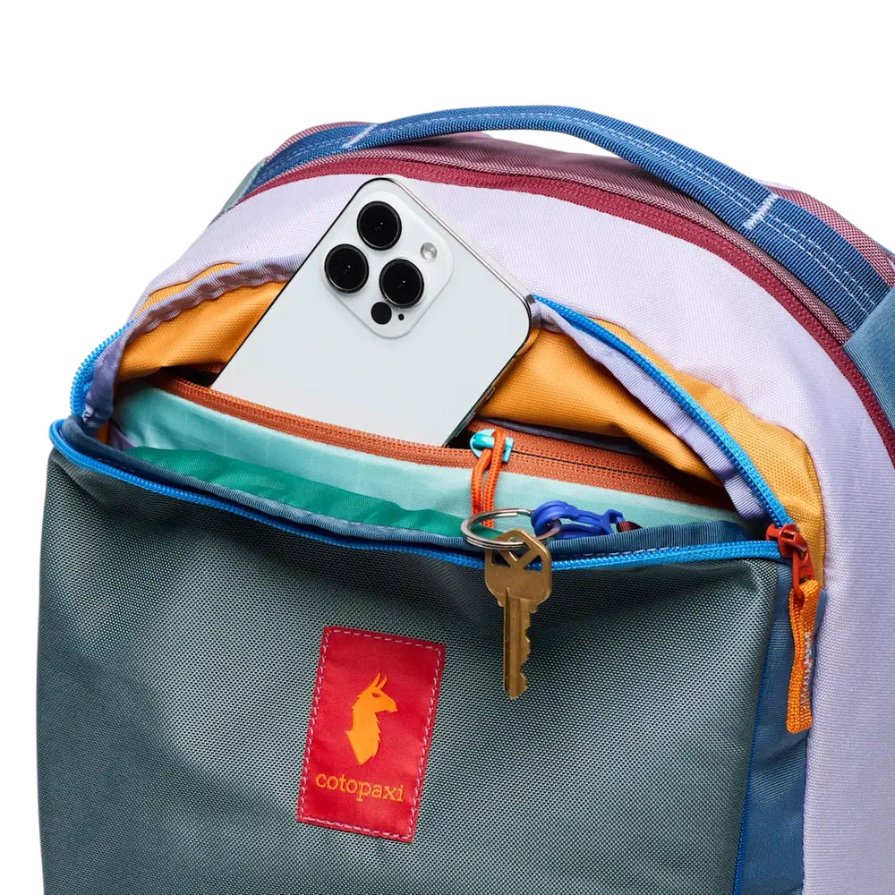Cotopaxi Allpa 18L Daypack in teal front pocket with orange zipper, multicolor interior, and a phone tucked inside.
