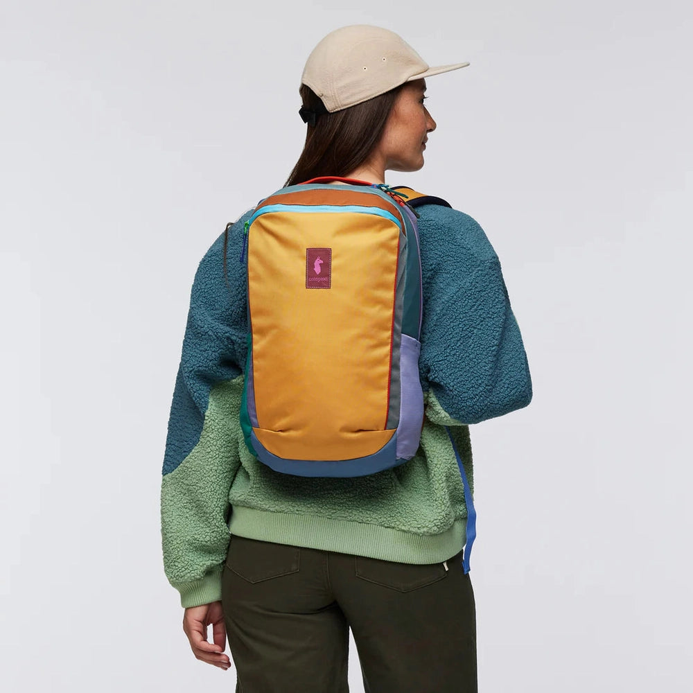 Cotopaxi Allpa 18L Daypack in mustard-yellow with teal side panels, purple zipper trim, pink logo patch