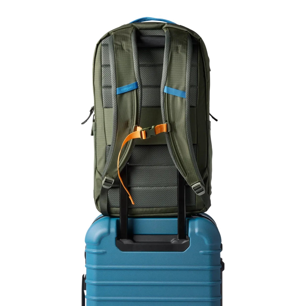Cotopaxi Allpa 26L Daypack in Olive Green with blue accents, rear view atop blue rolling suitcase.