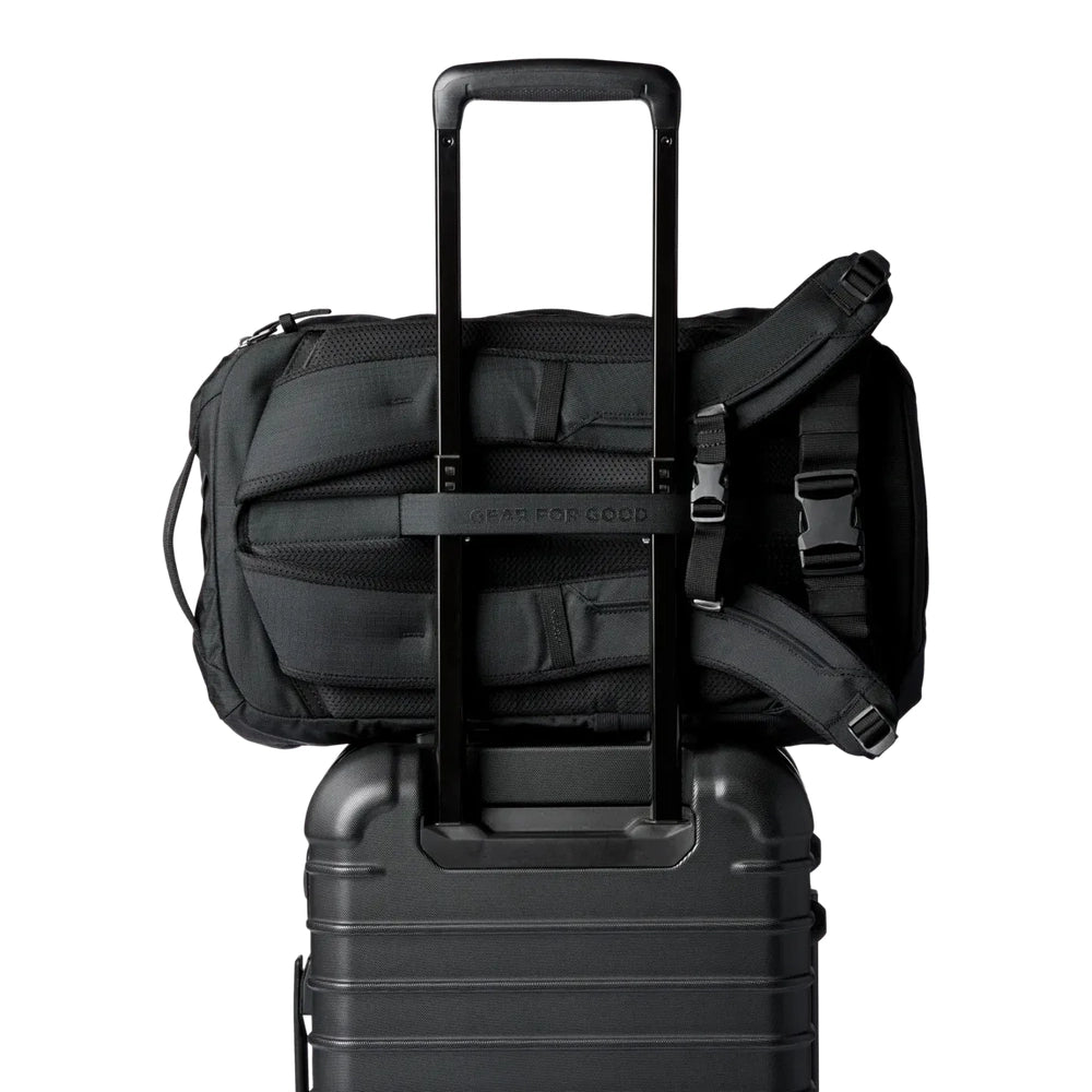 Cotopaxi Allpa 28L Travel Pack in black strapped to rolling suitcase with extended handle