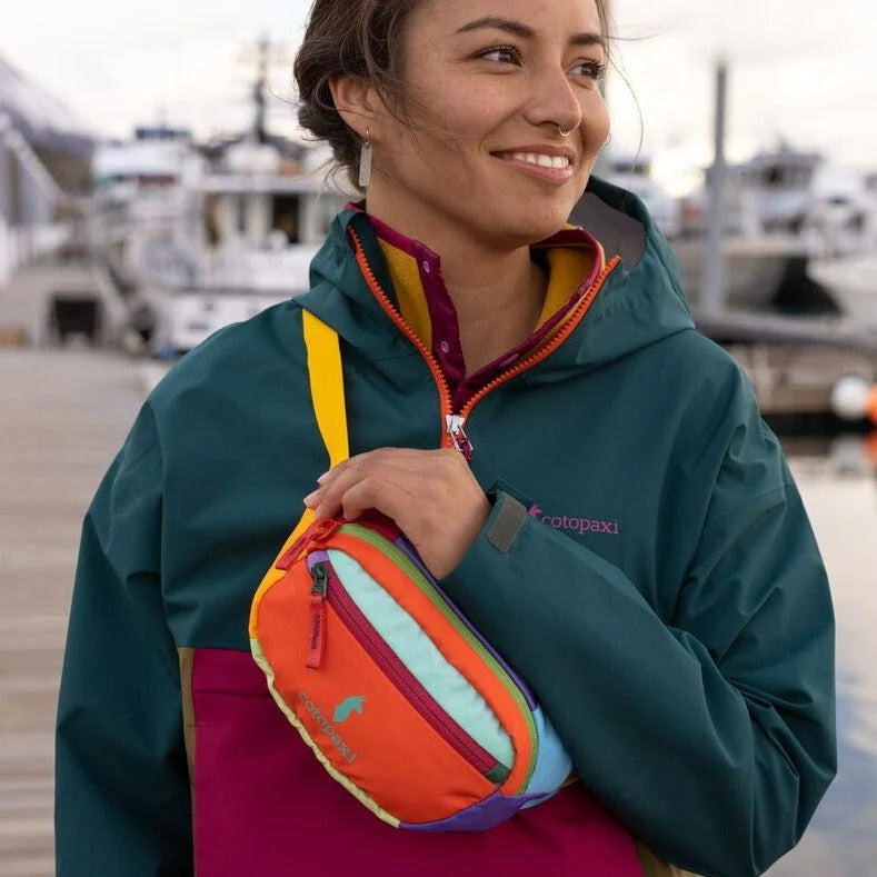 Cotopaxi Kapai 1.5L Hip Pack in multicolor patchwork with orange zipper and yellow strap