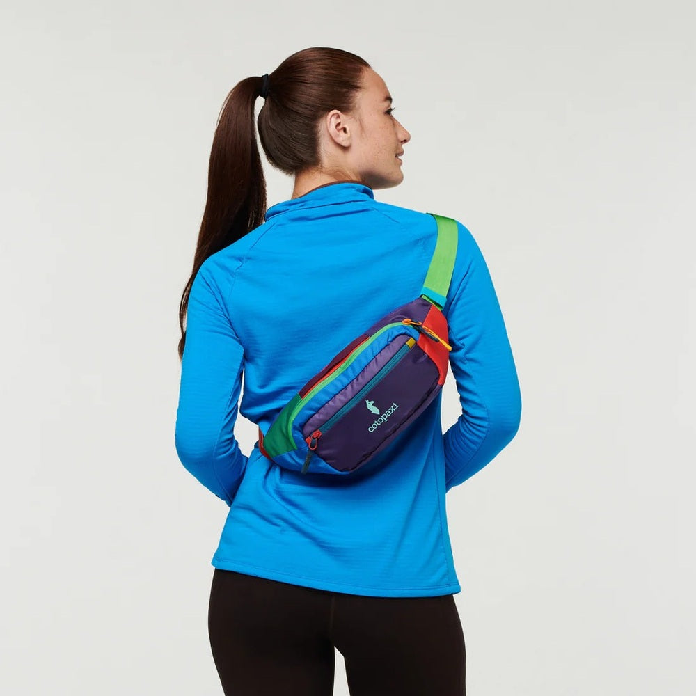 Person wearing a colorful waist bag on a plain background