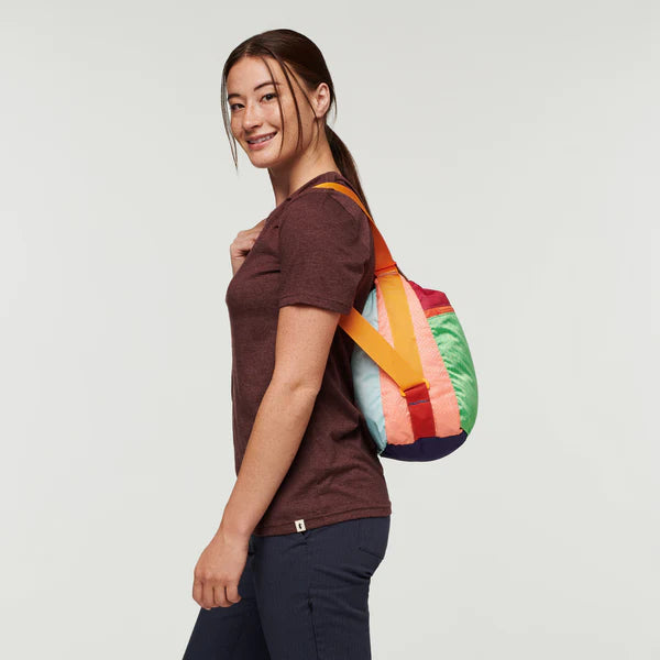 Cotopaxi Taal Convertible Tote in multicolor color-block, worn as a backpack with orange straps.