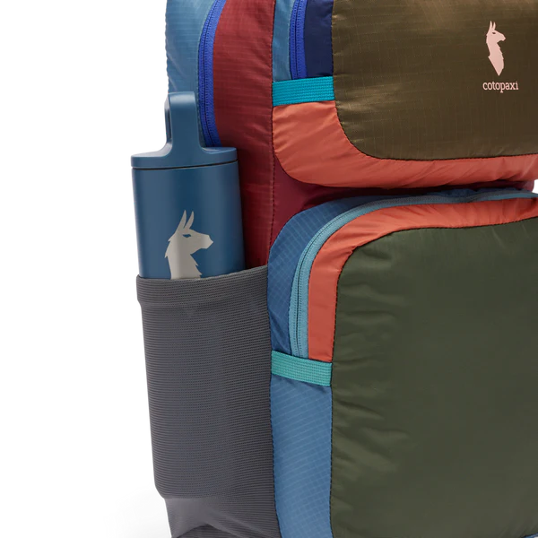 Cotopaxi Tasra 16L Backpack in multi-color blocks with side bottle pocket and blue water bottle.