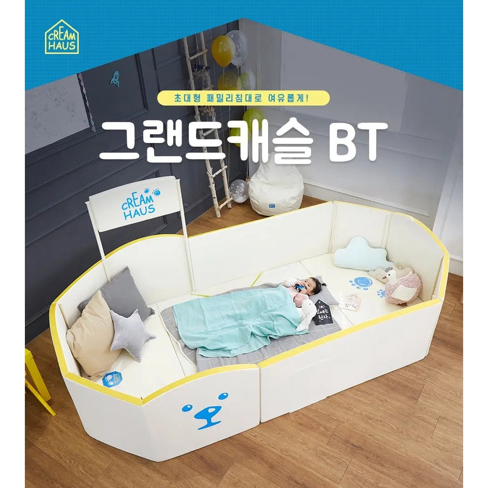 Creamhaus Grand Ice Castle Up BT baby playpen in white with yellow trim, where a child rests cozily inside.