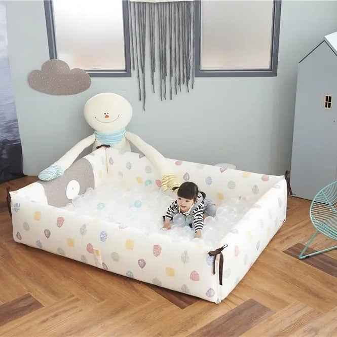 Creamhaus Inua Bumper Bed Guard XL in white with pastel dots; toddler sits inside the padded bed.