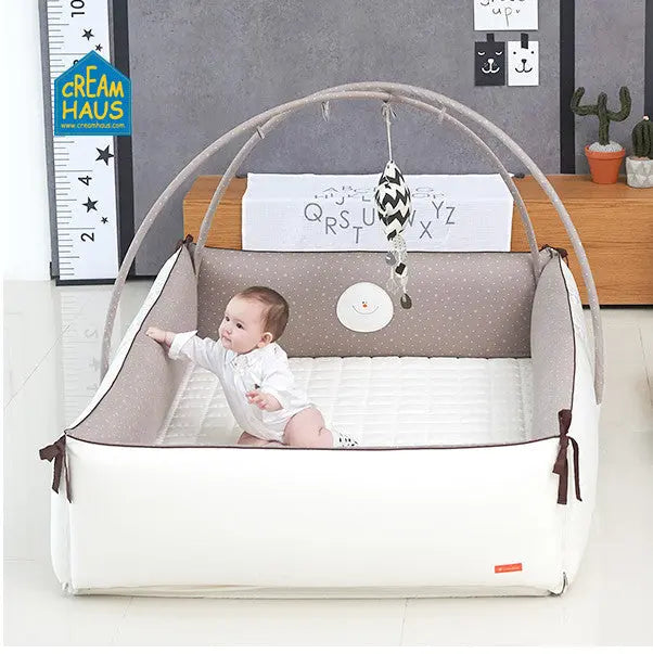 Creamhaus Inua Bumper Bed Guard XL: white base with grey dotted sides; baby sits inside under curved safety arch.