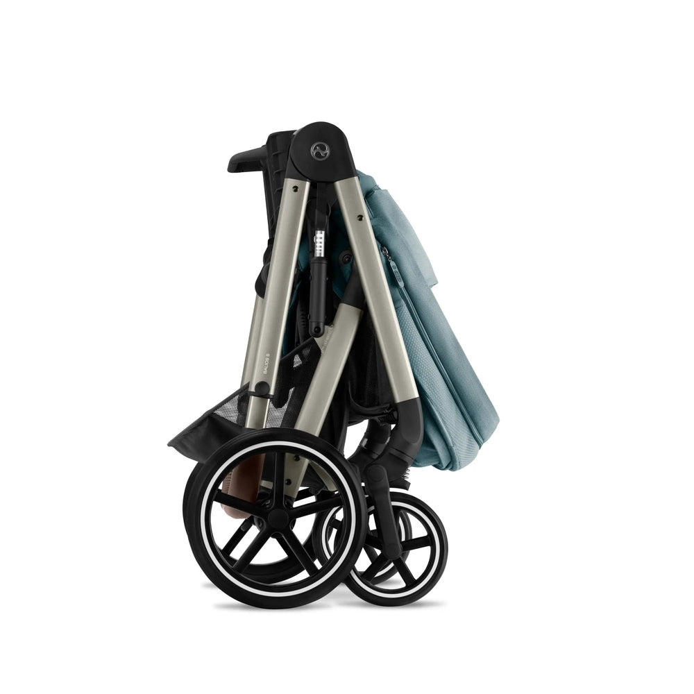 Cybex Balios S Lux stroller folded compactly with teal fabric, silver frame, and black wheels.
